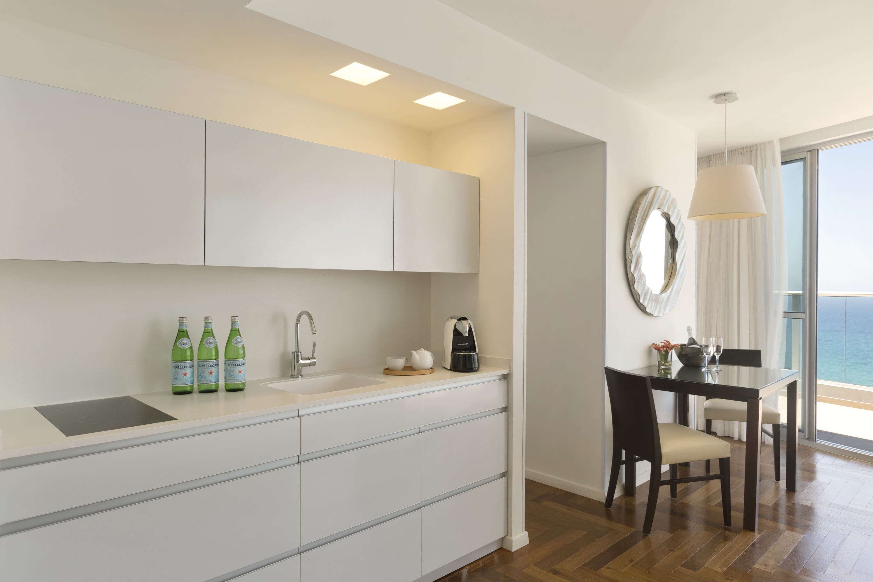Une cuisine moderne avec des meubles blancs, un évier et un coin repas comprenant une table et des chaises.