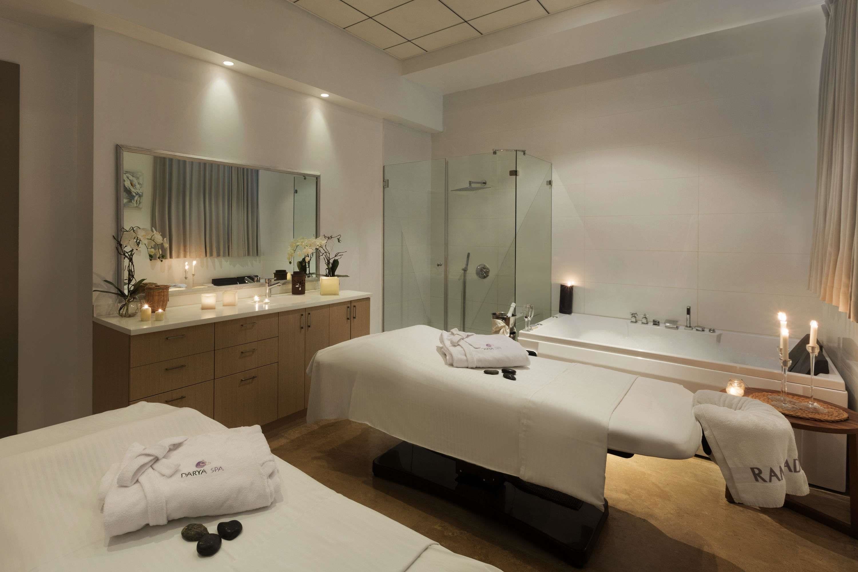 Une salle de spa moderne équipée de deux tables de massage, d’une grande baignoire et d’un espace douche séparé.