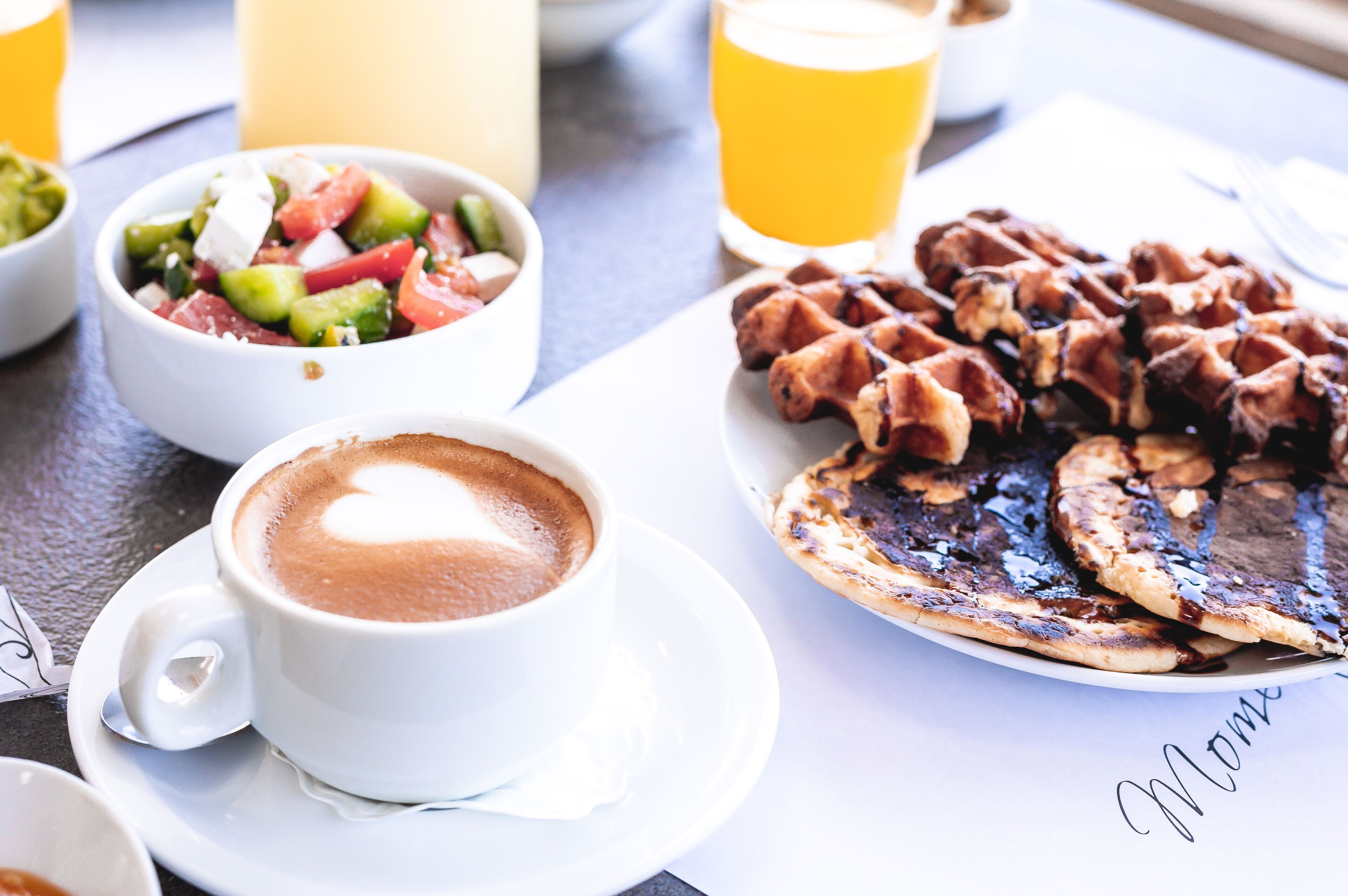 A breakfast setting with a cup of coffee, waffles, and a fruit salad.