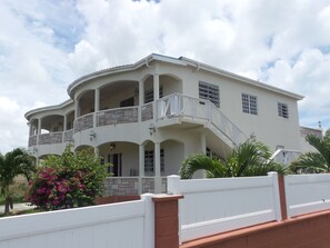 A large, multi-story building with a white exterior, multiple balconies, and a central staircase. - Suite Serenade (St. John's)