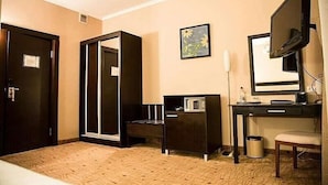A hotel room with a bed, a desk with a computer, a television, and a small cabinet.