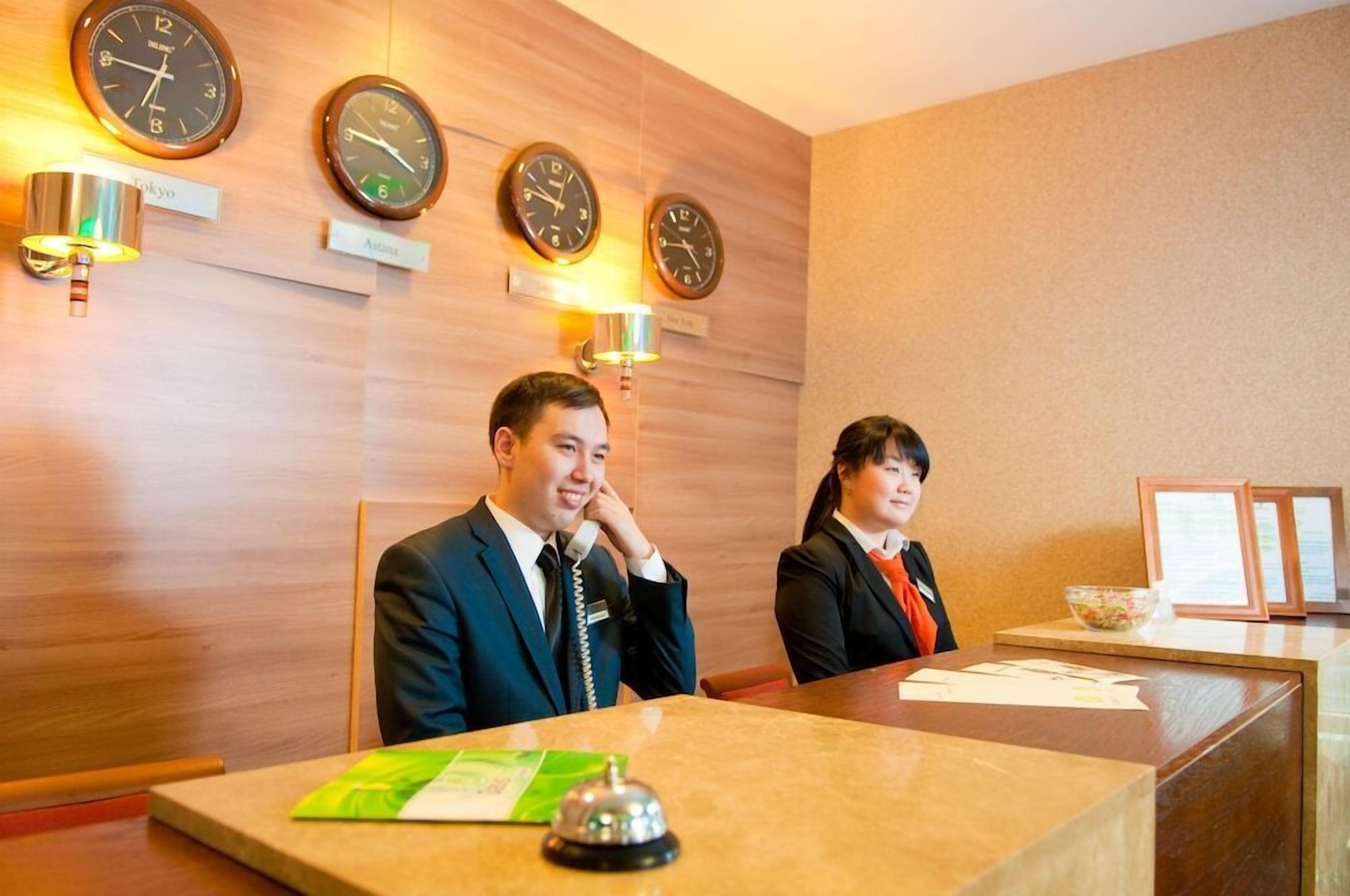 Ein Hotel-Empfangsbereich mit Holzvertäfelung, Uhren und einem Empfangstresen.