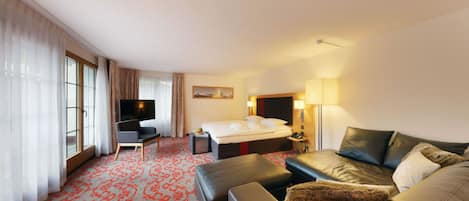Una habitación de hotel con una cama grande, un sofá, un televisor y un escritorio.