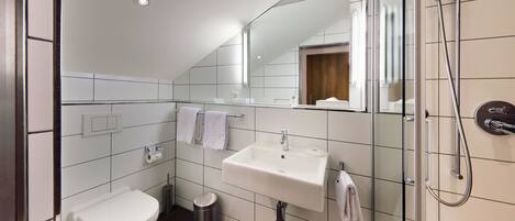 Un baño moderno con inodoro, lavamanos y ducha.