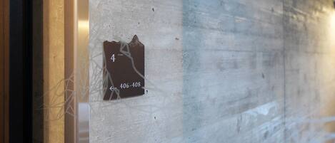 Una pared con una sección dañada que muestra el número '4' y el número de teléfono '406-408'.