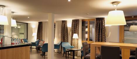 A hotel lobby with a reception desk, seating area, and a bar.