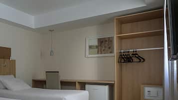 Une chambre d’hôtel avec deux lits, un bureau, un petit réfrigérateur et une armoire.