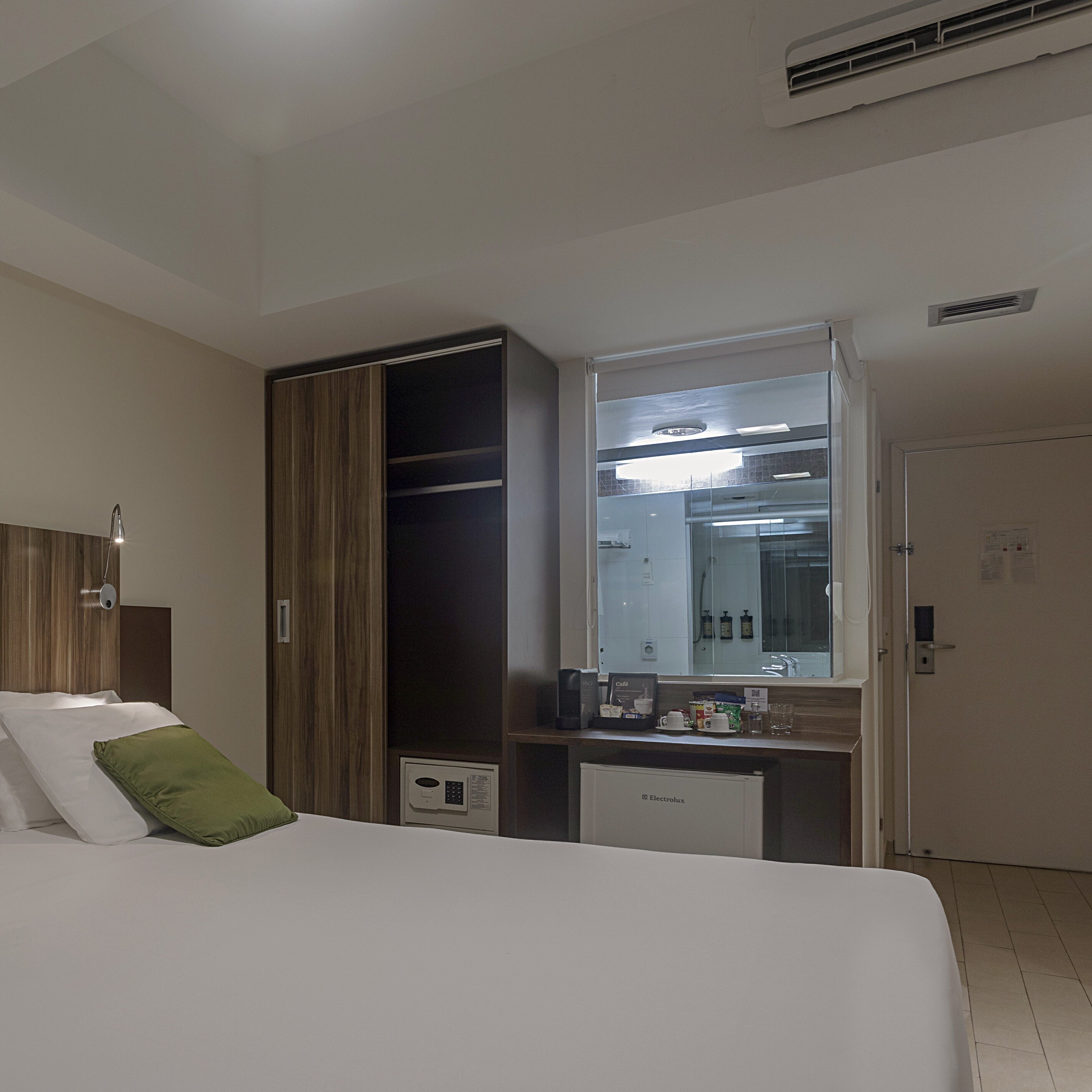 Una camera d'albergo con un letto, una scrivania, uno specchio e un armadio.