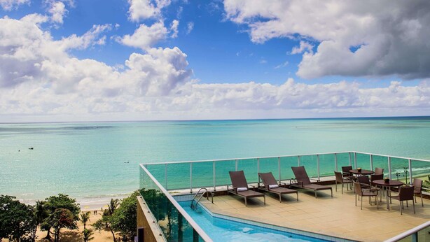 A rooftop pool with lounge chairs and a view of the ocean. - Mercure Maceio Pajucara Hotel (Maceió)