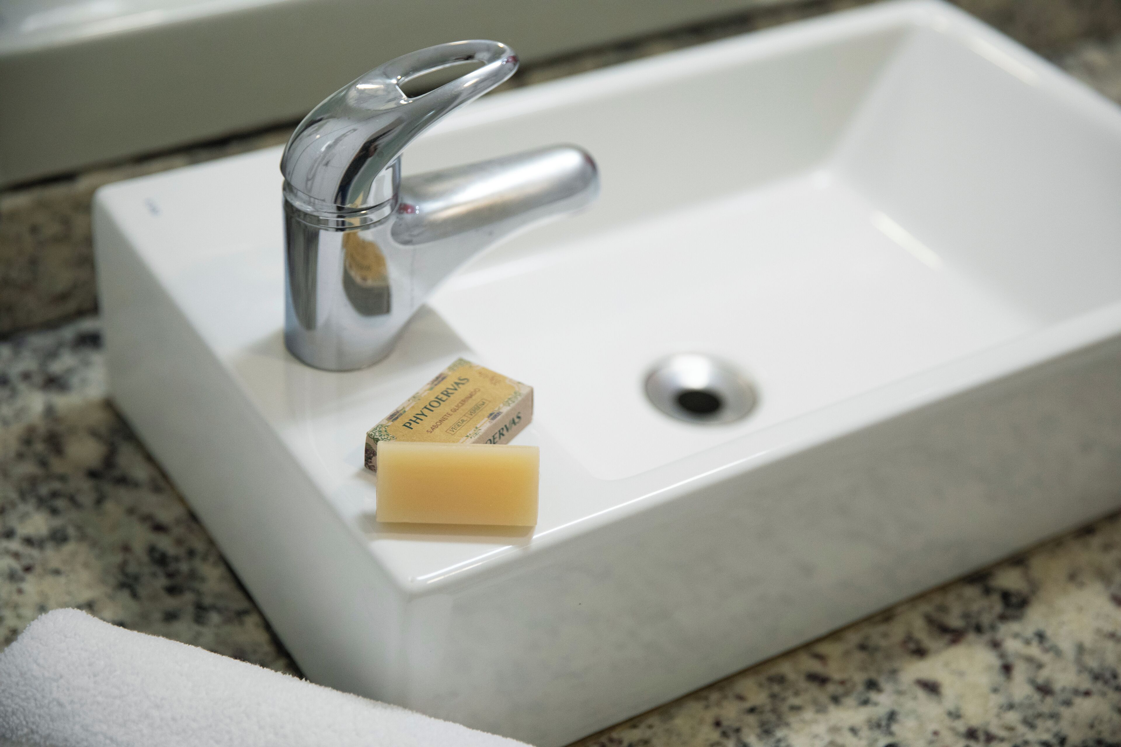 A white rectangular sink with a chrome faucet and a soap bar.