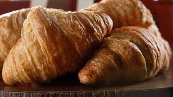 Zwei Croissants auf einer Holztischplatte.