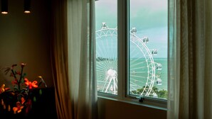 A room with a large window overlooking a Ferris wheel. - Mercure Maceio Pajucara Hotel (Maceió)