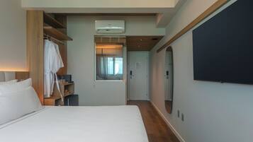 A hotel room with a large bed, a wardrobe, a mirror, and a television.