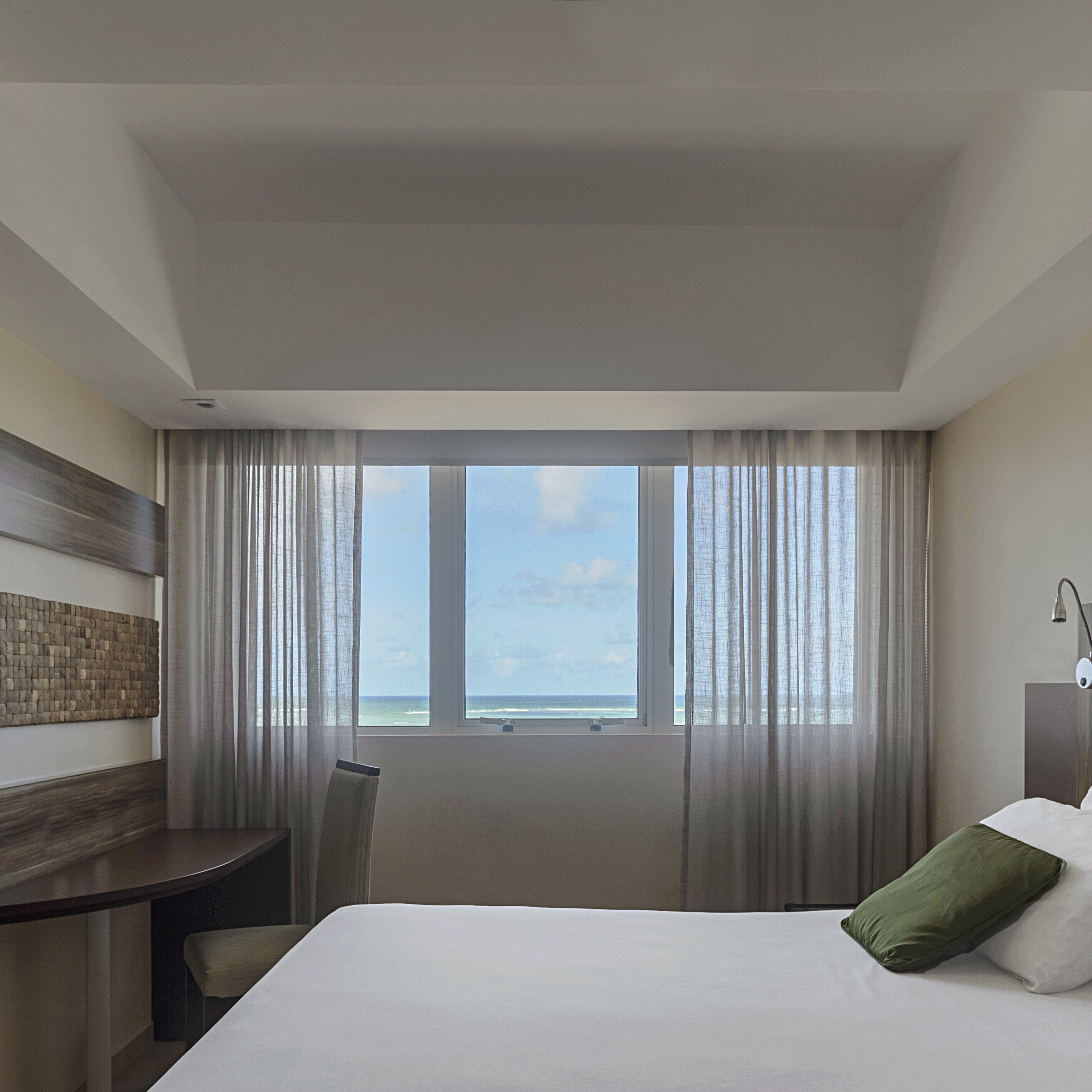 Una habitación de hotel con cama, escritorio y vista al océano.