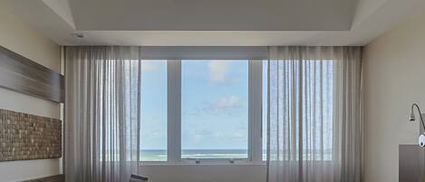 Una habitación de hotel con cama, escritorio y vista al océano.
