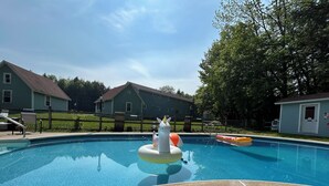 Una piscina con un flotador de unicornio y un cartel de advertencia sobre la ausencia de socorrista.