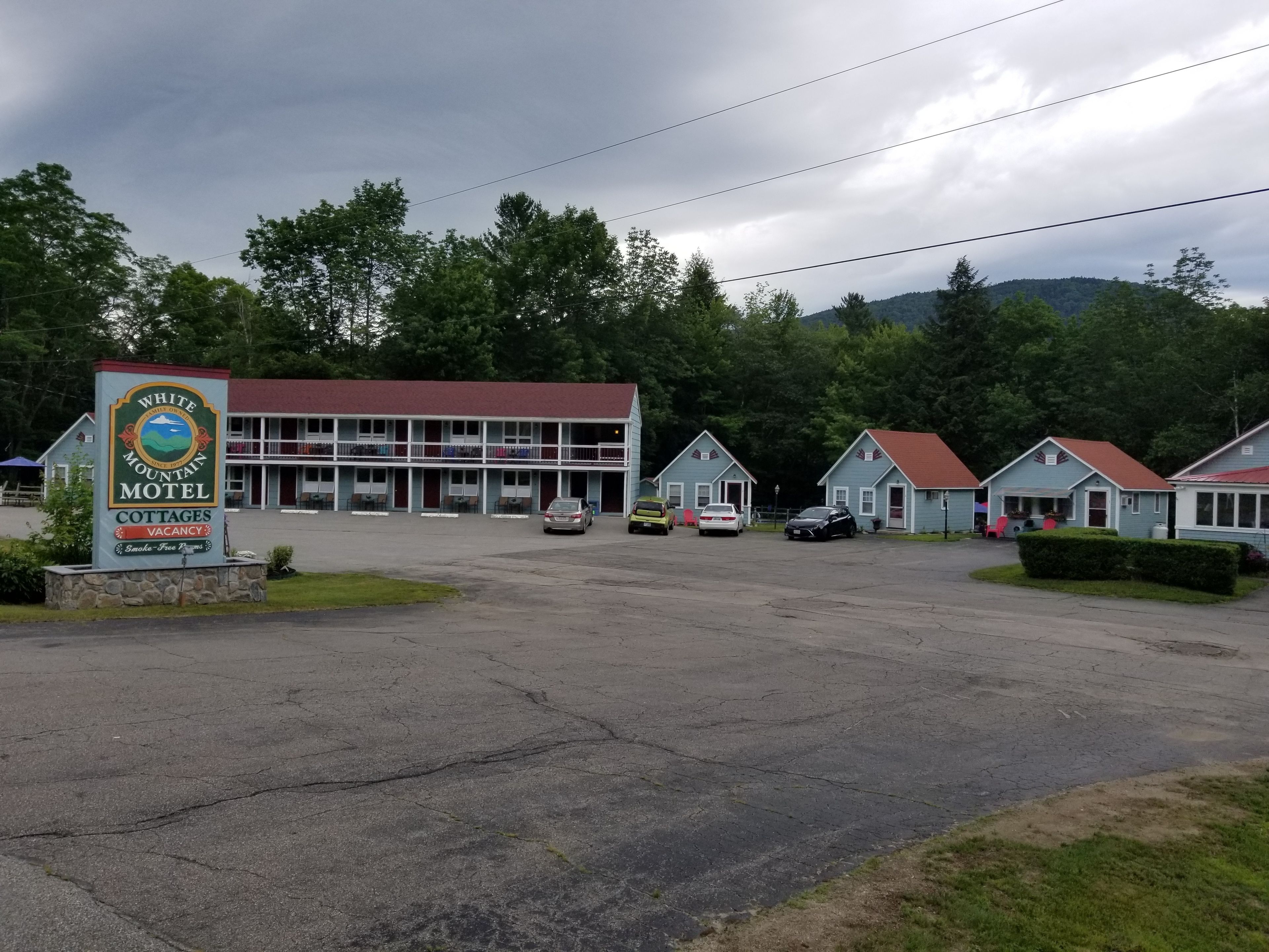 A motel with a signboard, a parking lot, and several cottages.