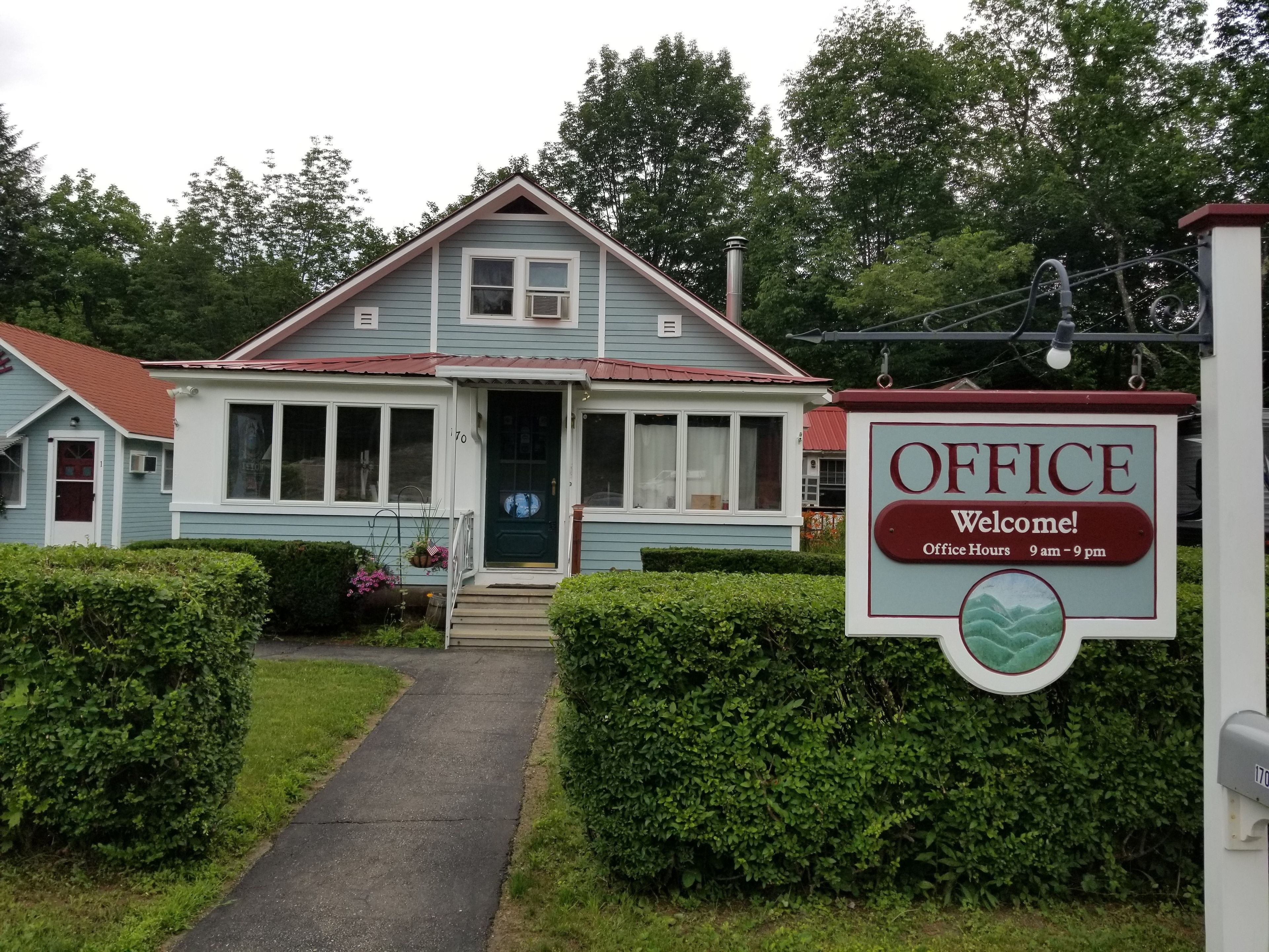 A two-story building with a sign indicating office hours.