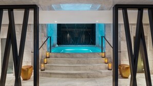 Un espace spa doté d’un jacuzzi, de marches en marbre et d’un éclairage à la bougie.