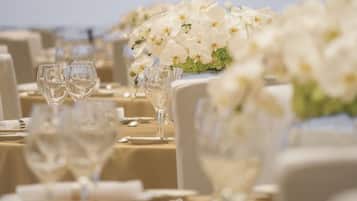 A banquet table set with white tablecloths, clear glassware, and white flowers.
