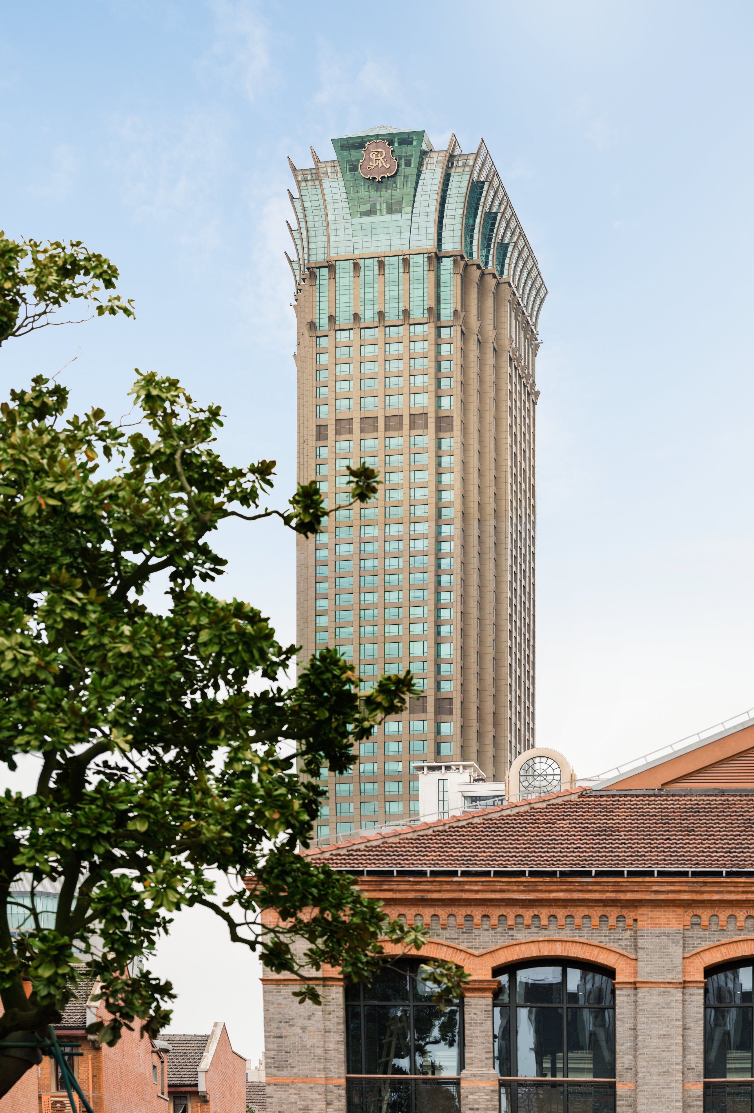Een hoog gebouw met een opvallend dak en een lager gebouw met pannendak op de voorgrond.