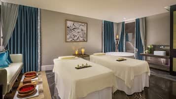 Relax in a serene spa room with two massage tables, a round bathtub, and a marble vanity.