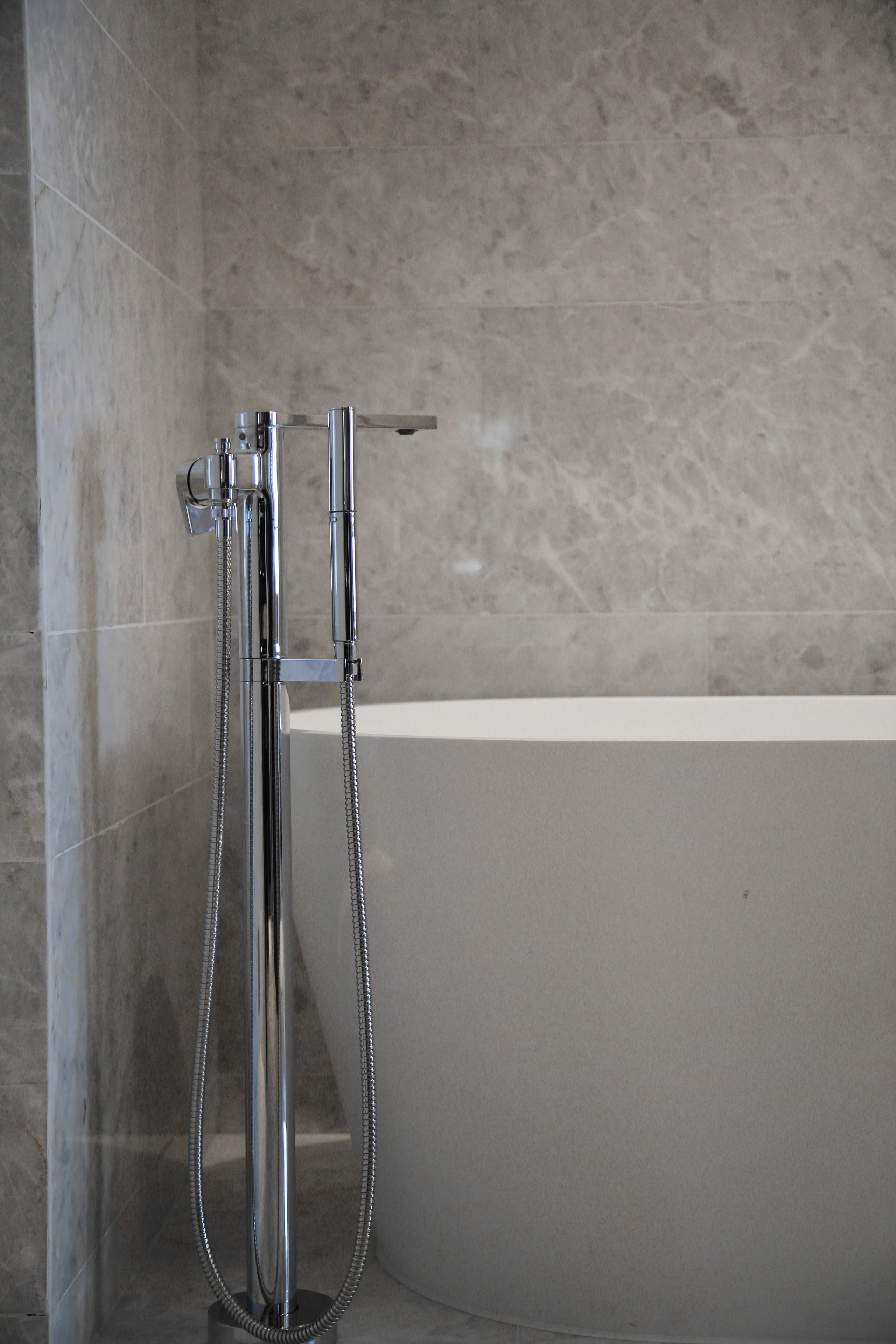 A modern bathroom with a standalone bathtub and a handheld showerhead.