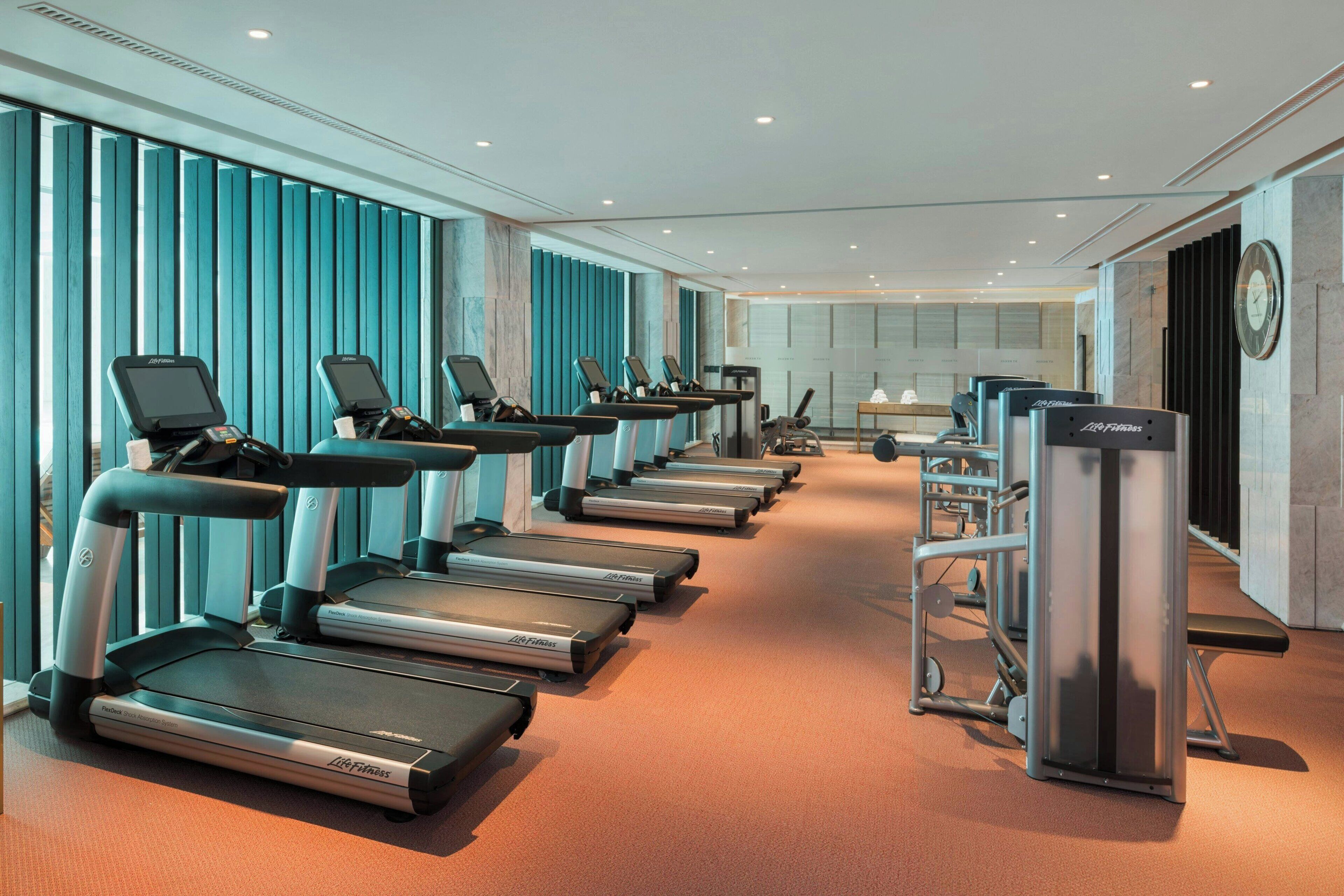 Un gimnasio con cintas de correr, elípticas y máquinas de pesas.