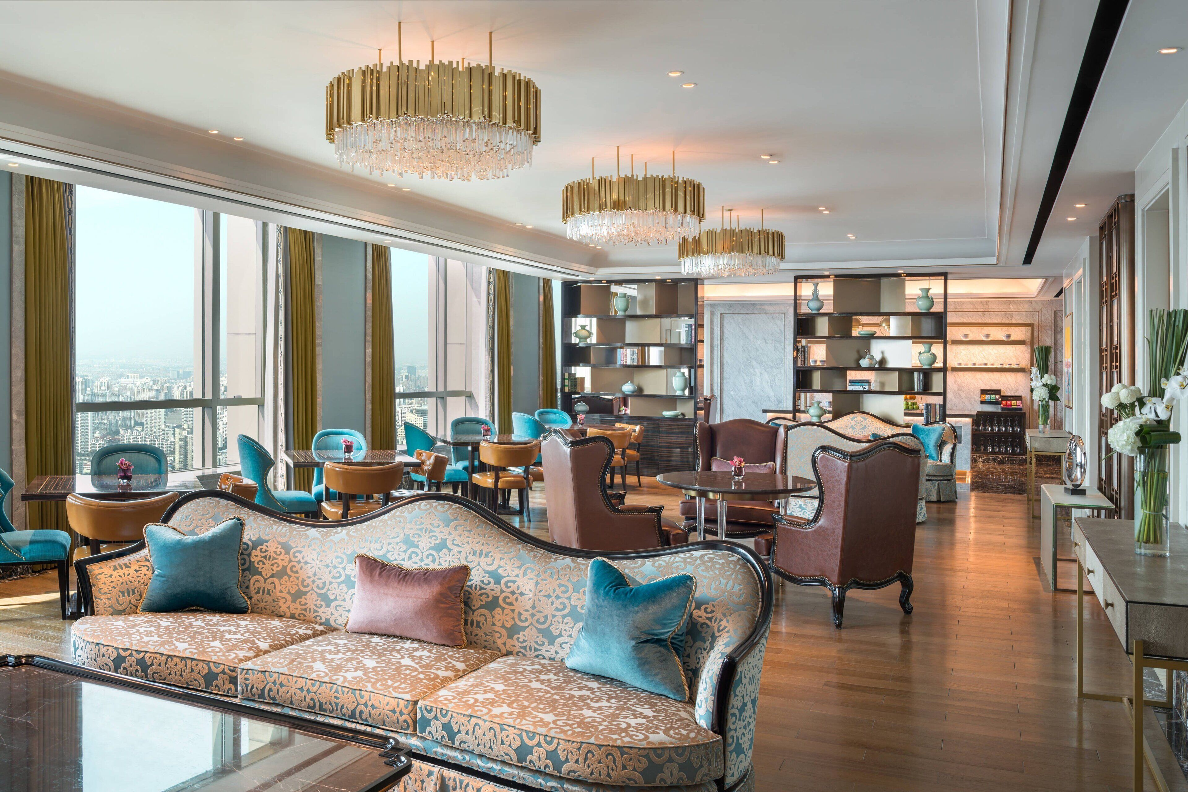 Un amplio lobby de hotel con una gran zona de estar, ambiente luminoso y vistas a la ciudad a través de amplios ventanales.