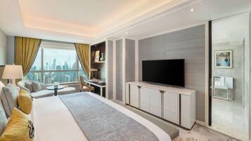 A modern hotel room with a large bed, a flat-screen TV, a desk, and a city view.