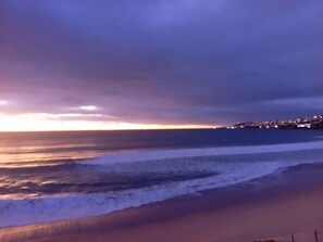 Une plage avec des vagues et, au loin, la silhouette d’une ville.