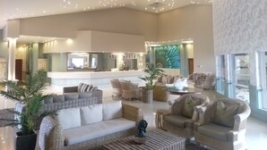 A spacious living area with a high ceiling, multiple seating options, and a kitchen in the background. - Diaz Hotel & Resort (Mossel Bay)