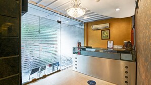 A reception area with a modern design, featuring a glass partition, a reception desk, and a chandelier.