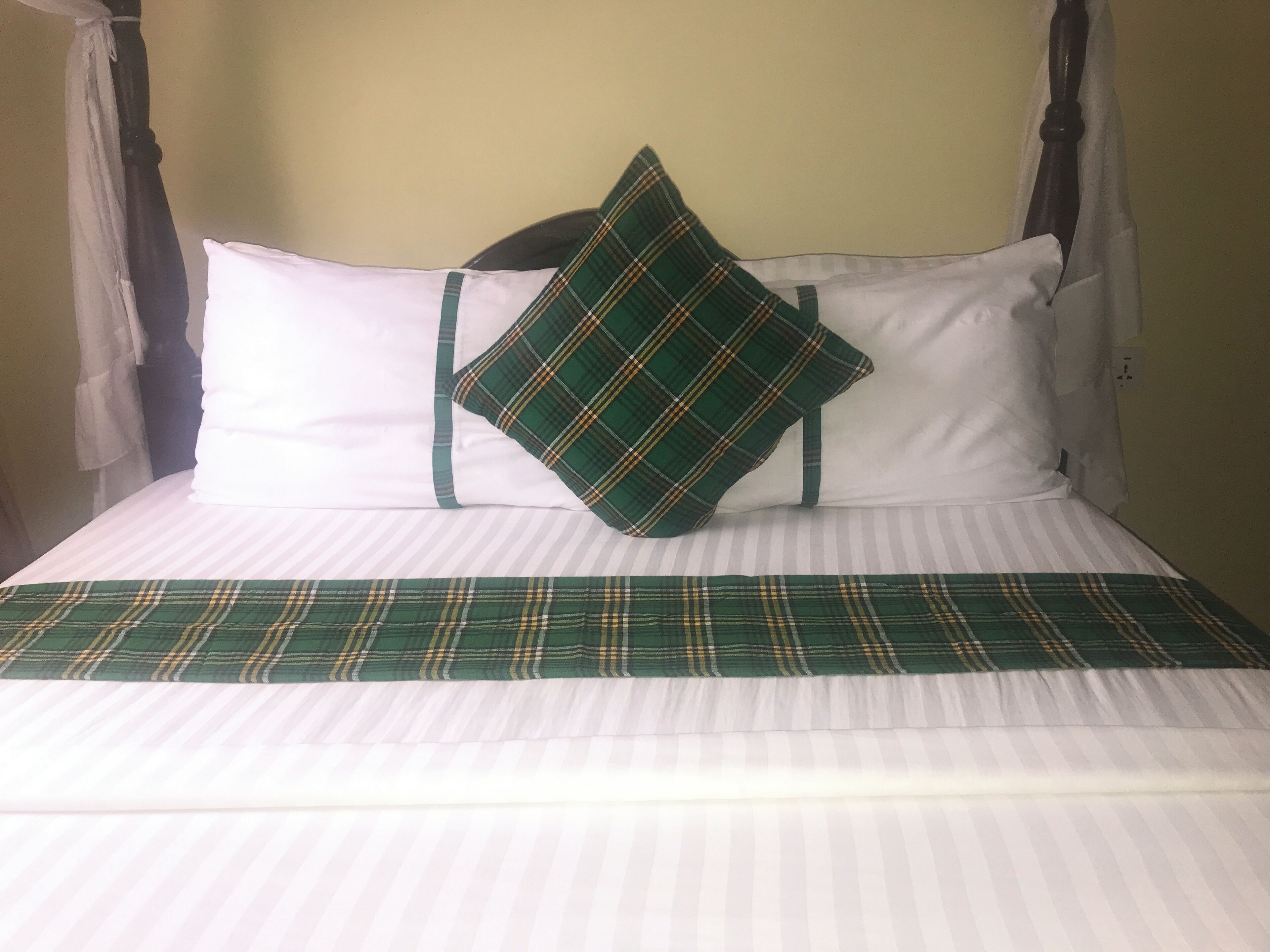 A bed with a plaid bedspread, two pillows, and a headboard.