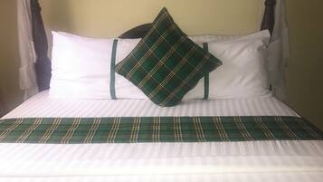 A bed with a plaid bedspread, two pillows, and a headboard.