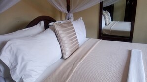 A neatly made bed with white and beige pillows, a textured white bedspread, and a canopy overhead.