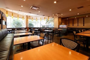 A restaurant interior with multiple tables and booths, pendant lighting, and large windows. - Kurume Washington Hotel Plaza (Kurume)