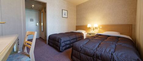 Een hotelkamer met twee bedden, een bureau en een stoel.