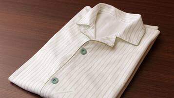 A neatly folded white shirt with green buttons on a wooden surface.
