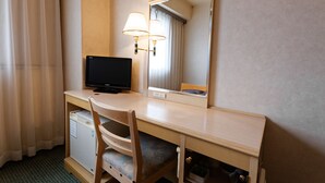 Een hotelkamer met een houten bureau, een televisie, een spiegel en een lamp.