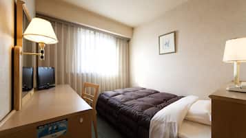 A hotel room with a bed, a desk with a lamp, a chair, a television, and a window with curtains.