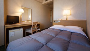 Een hotelkamer met een bed, bureau, stoel, televisie en koelkast.