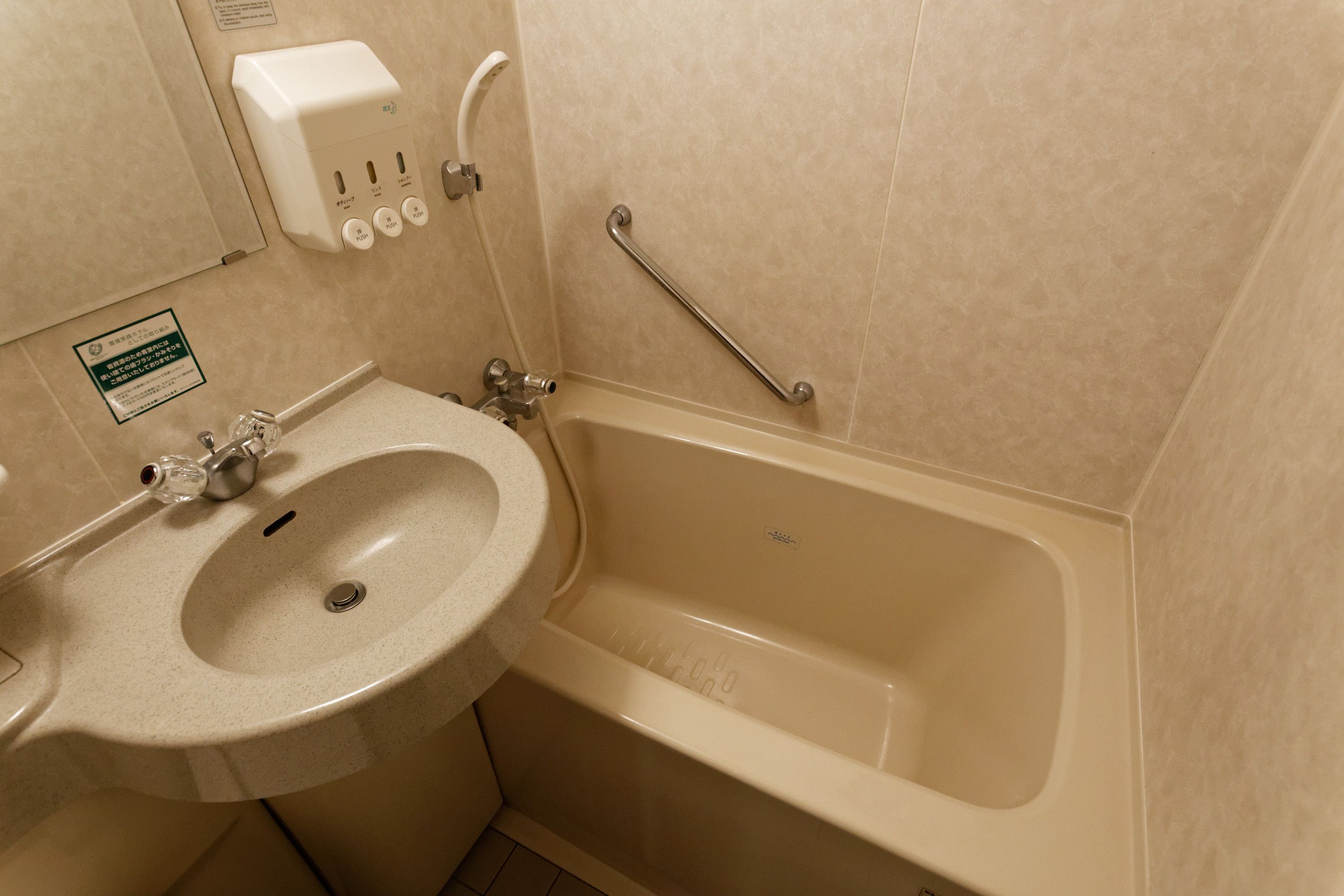 Un baño con lavamanos, bañera y dispensador de gel antibacterial.