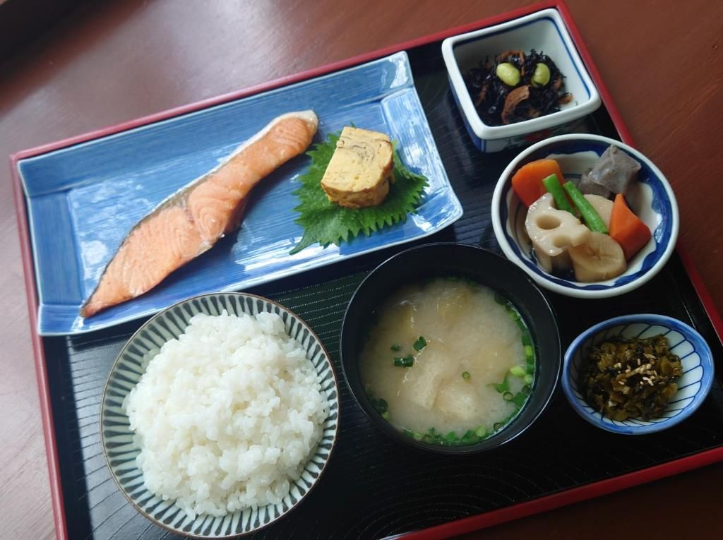 A meal tray with a fish, tofu, rice, soup, and various side dishes.