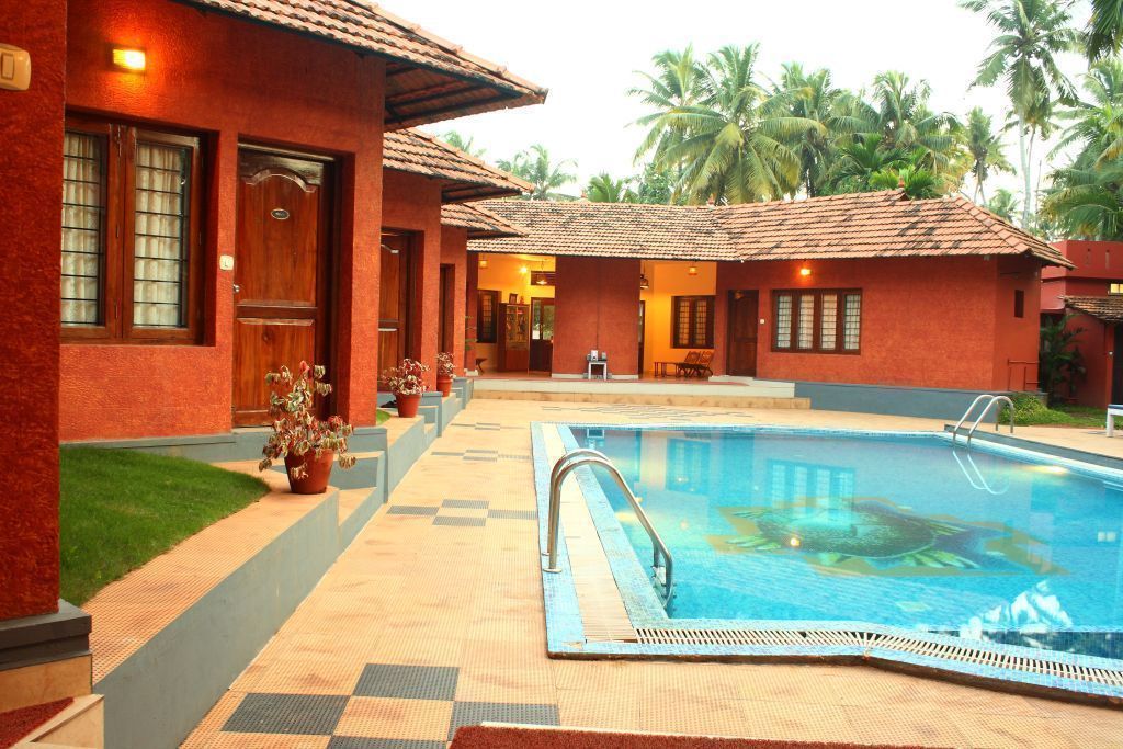 A swimming pool area with a tiled deck, a pool with a metal ladder, and a building with a tiled roof and windows.