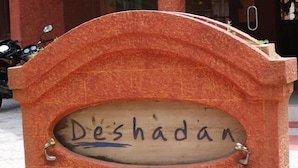 A sign with the name 'Deshadan' carved into it, mounted on a stone structure.