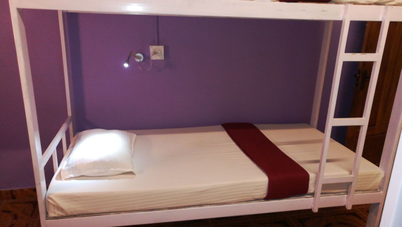 A bunk bed with a white frame, a red blanket, and a white pillow.