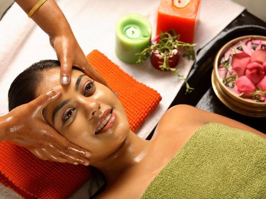 A person receiving a facial treatment with a towel and a green towel on their shoulder.