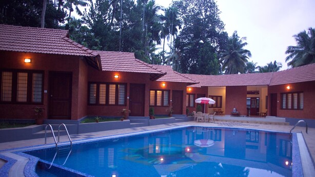A swimming pool with a tiled edge, surrounded by buildings with red-tiled roofs and windows.