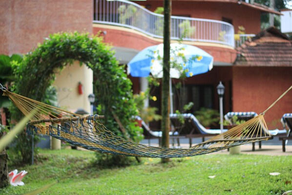 A hammock in a grassy area with a building in the background.
